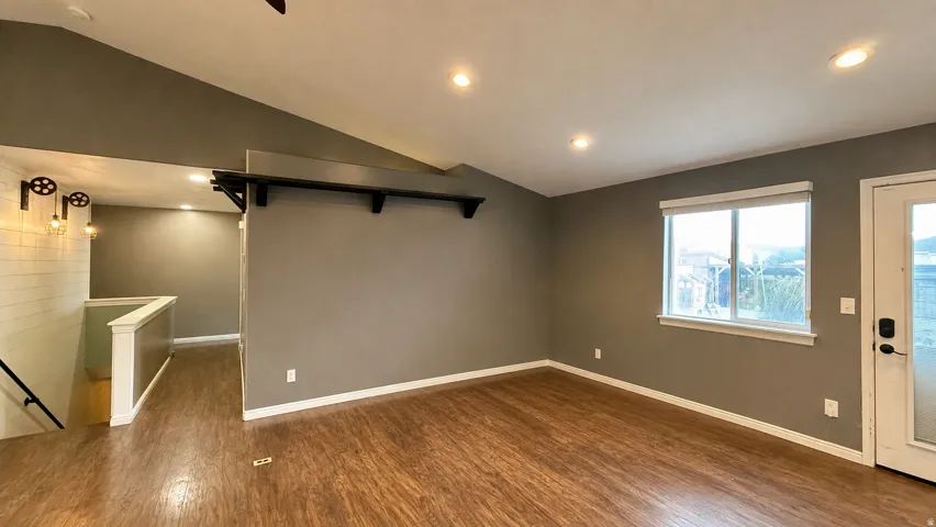 Wood-finish flooring throughout, vaulted ceiling, recessed lighting, and a white-framed window