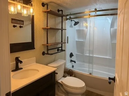 Bathroom featuring a dark wood-finish vanity with a light-toned countertop, a tub/shower combination, and wood-finish flooring
