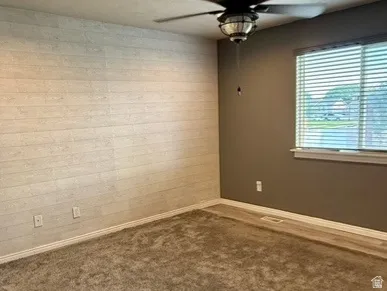 Wood-finish flooring with a textured accent wall and a window with horizontal blinds