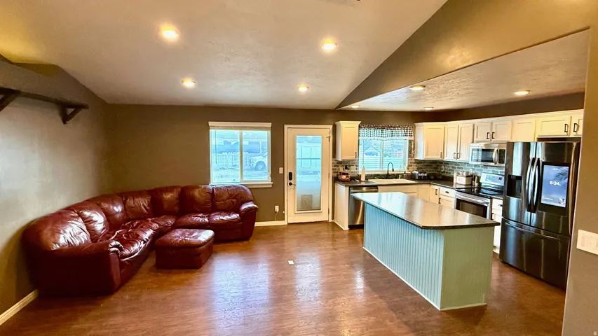 Open-concept living area featuring wood-finish flooring, recessed lighting, and a white kitchen with a center island