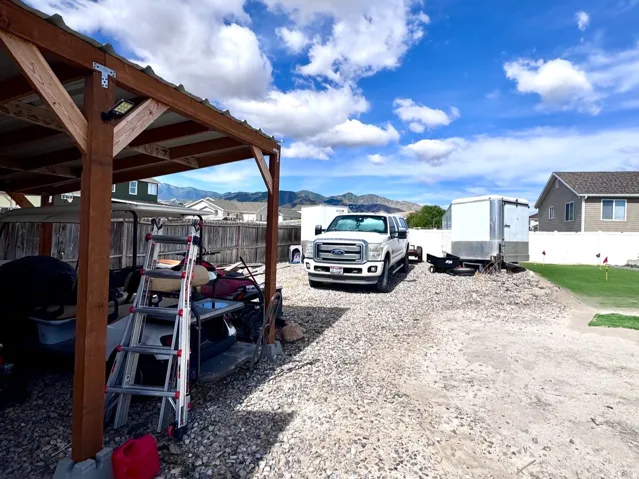 Gravel driveway with a wood-frame open-sided carport and a metal roof