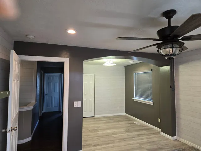 Archway entrance to a room featuring wood-finish flooring, recessed lighting, and a ceiling fan with light fixture