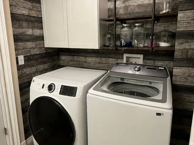 Wood-look plank wall covering with white upper cabinetry and dark metal shelving