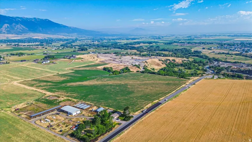 Expansive rural landscape featuring a paved roadway, agricultural fields, and distant mountain ranges