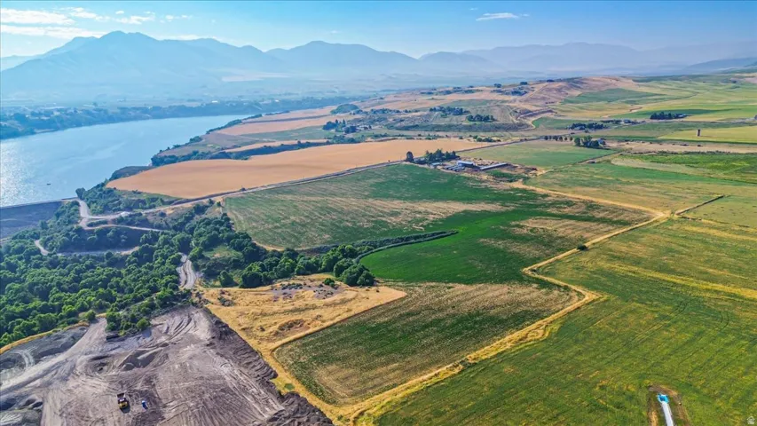 Expansive agricultural landscape featuring diverse fields, a prominent waterway, and distant mountain ranges