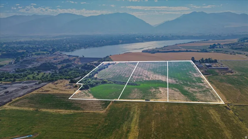 Expansive agricultural land featuring delineated parcels, a distant water body, and a mountainous backdrop