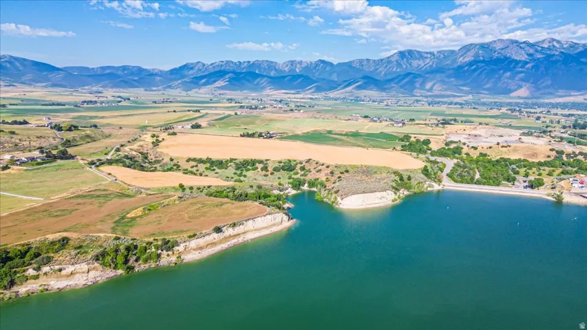 Expansive body of water bordered by undeveloped land and distant mountainous terrain under a clear sky