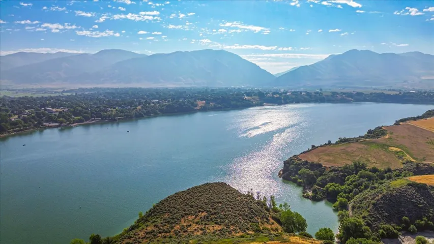 Expansive lake with surrounding land features, including distant mountains and a residential area