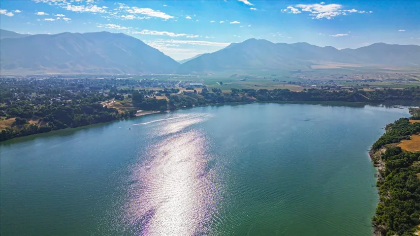Expansive body of water with surrounding green and golden-toned land, backed by distant mountains