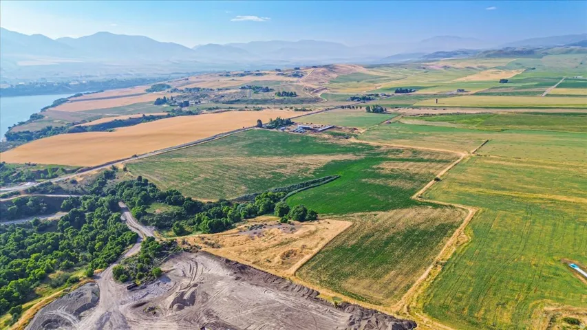 Expansive land parcel featuring diverse topography including cultivated fields, wooded areas, and a visible water body