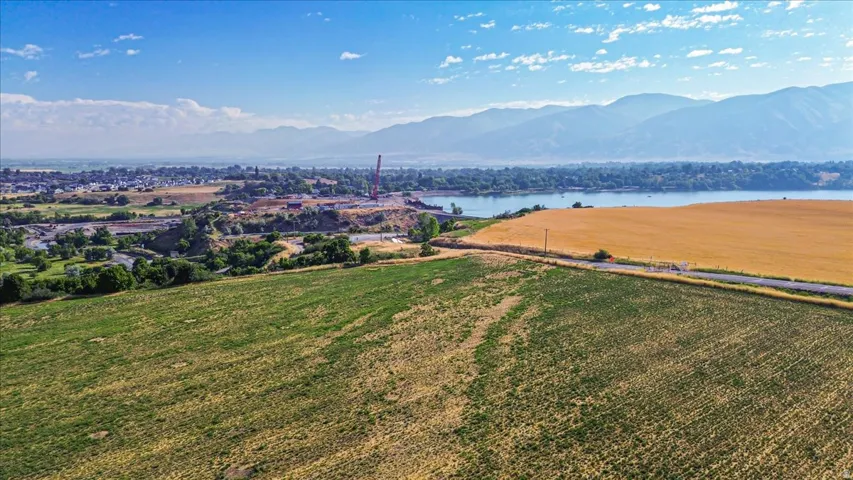 Expansive agricultural land featuring a lake backdrop and distant mountain ranges