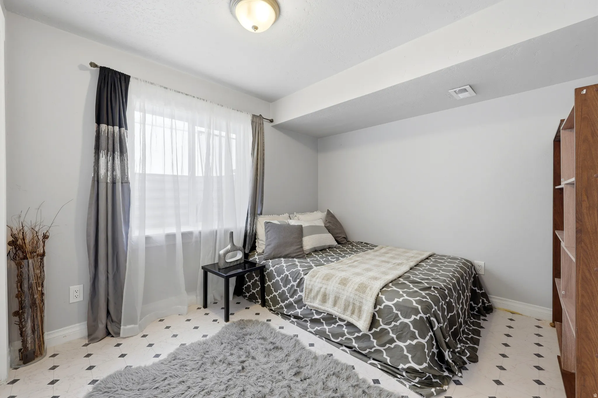 Room featuring a window with blinds, light gray walls, and patterned flooring