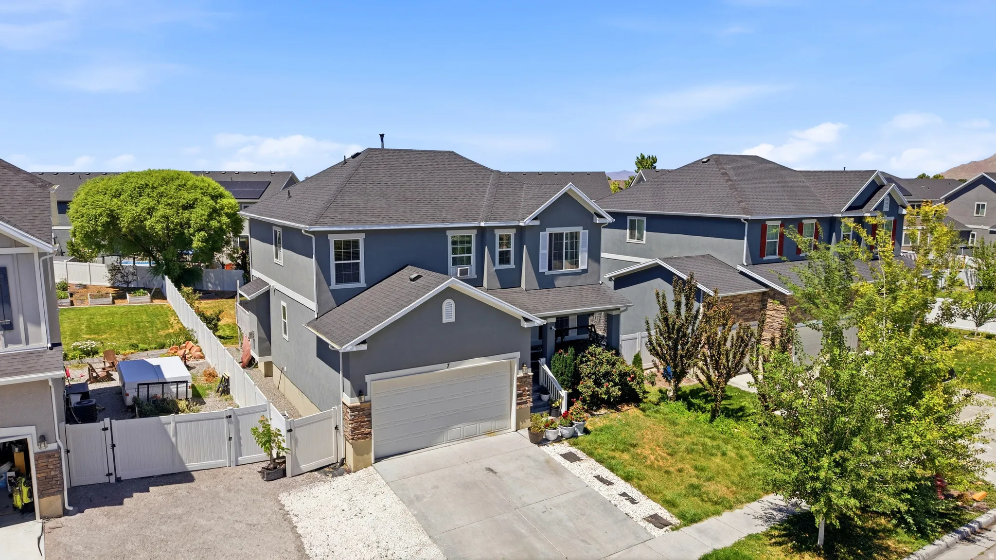Two-story residence featuring a gray exterior with stone accents and a white garage door