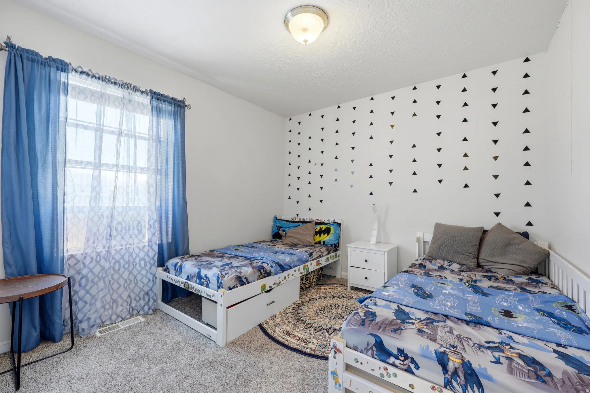 White-painted room featuring a window with blue and white sheer curtains