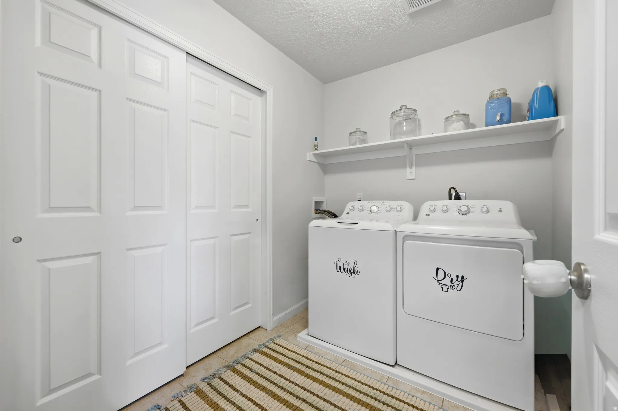 Dedicated laundry area featuring a built-in shelf, white paneled bifold doors, and wood-look flooring