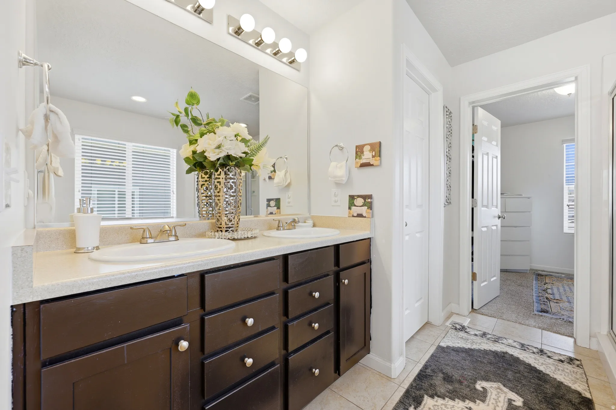 Double vanity featuring dark wood cabinetry, dual undermount sinks, and polished chrome fixtures