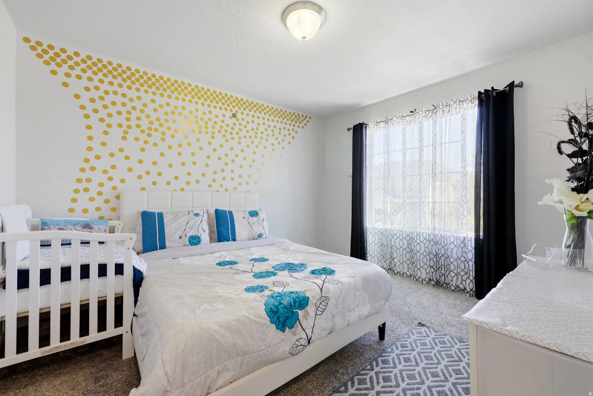 Bedroom featuring a window with dark curtains, white walls, and a textured ceiling