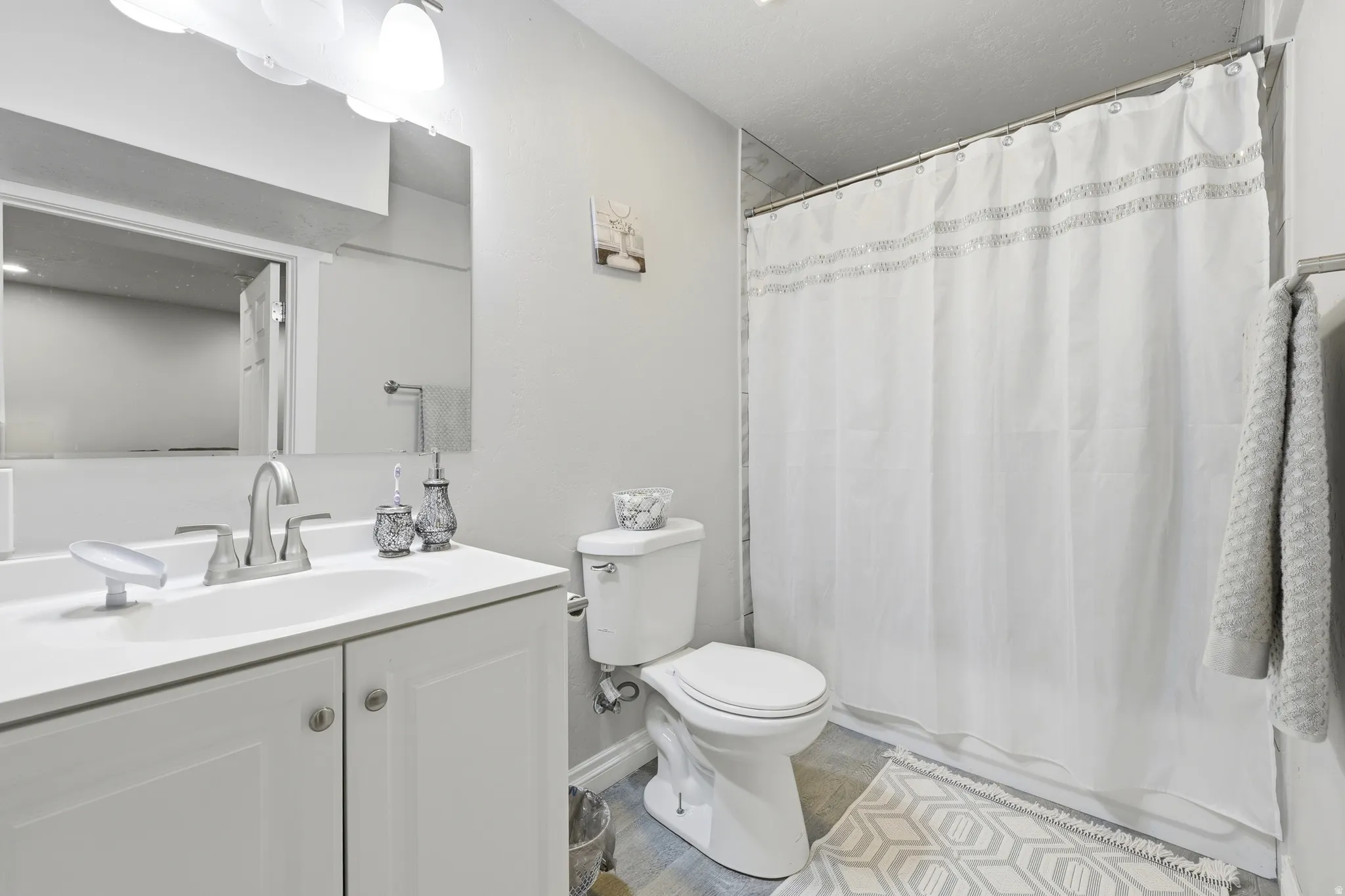 Bathroom featuring a white vanity with a single basin sink, brushed nickel faucet, and coordinated hardware