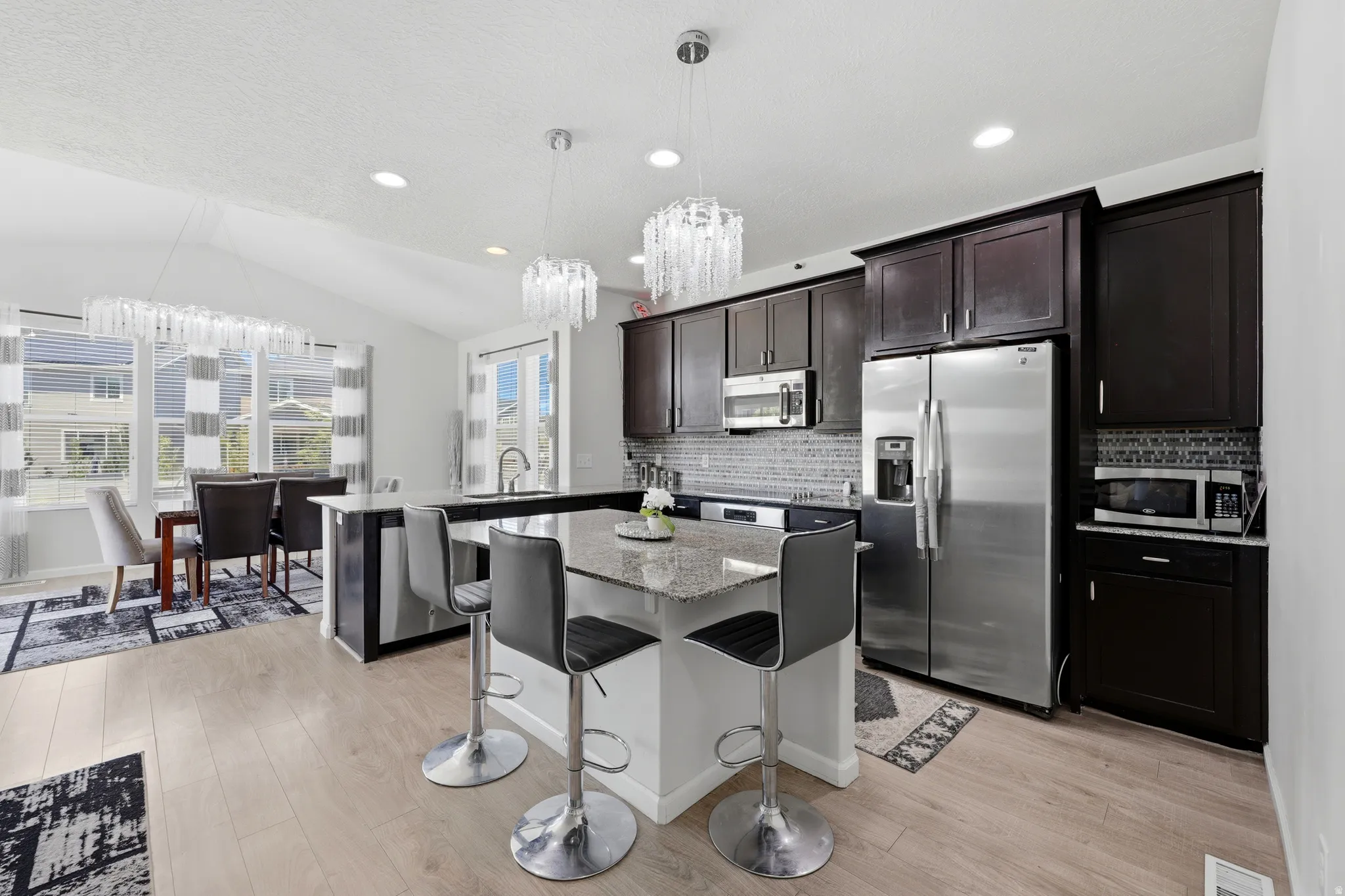 Contemporary kitchen with dark wood-finish cabinetry, stainless steel appliances, and a mosaic tile backsplash
