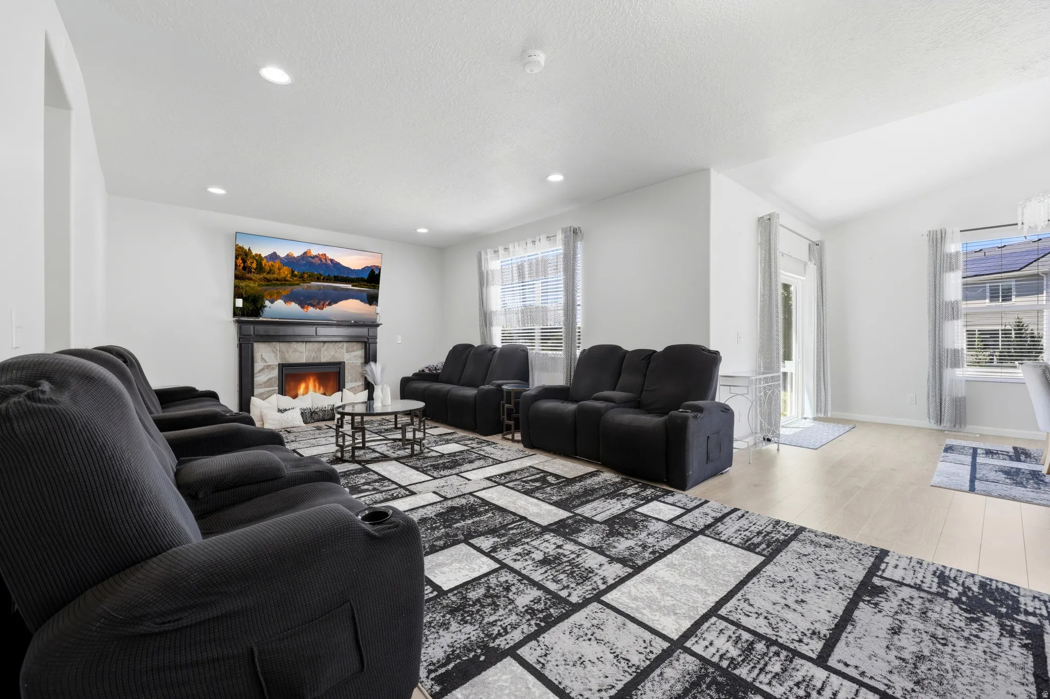 Living area with a stone fireplace, recessed lighting, and light wood-finish flooring