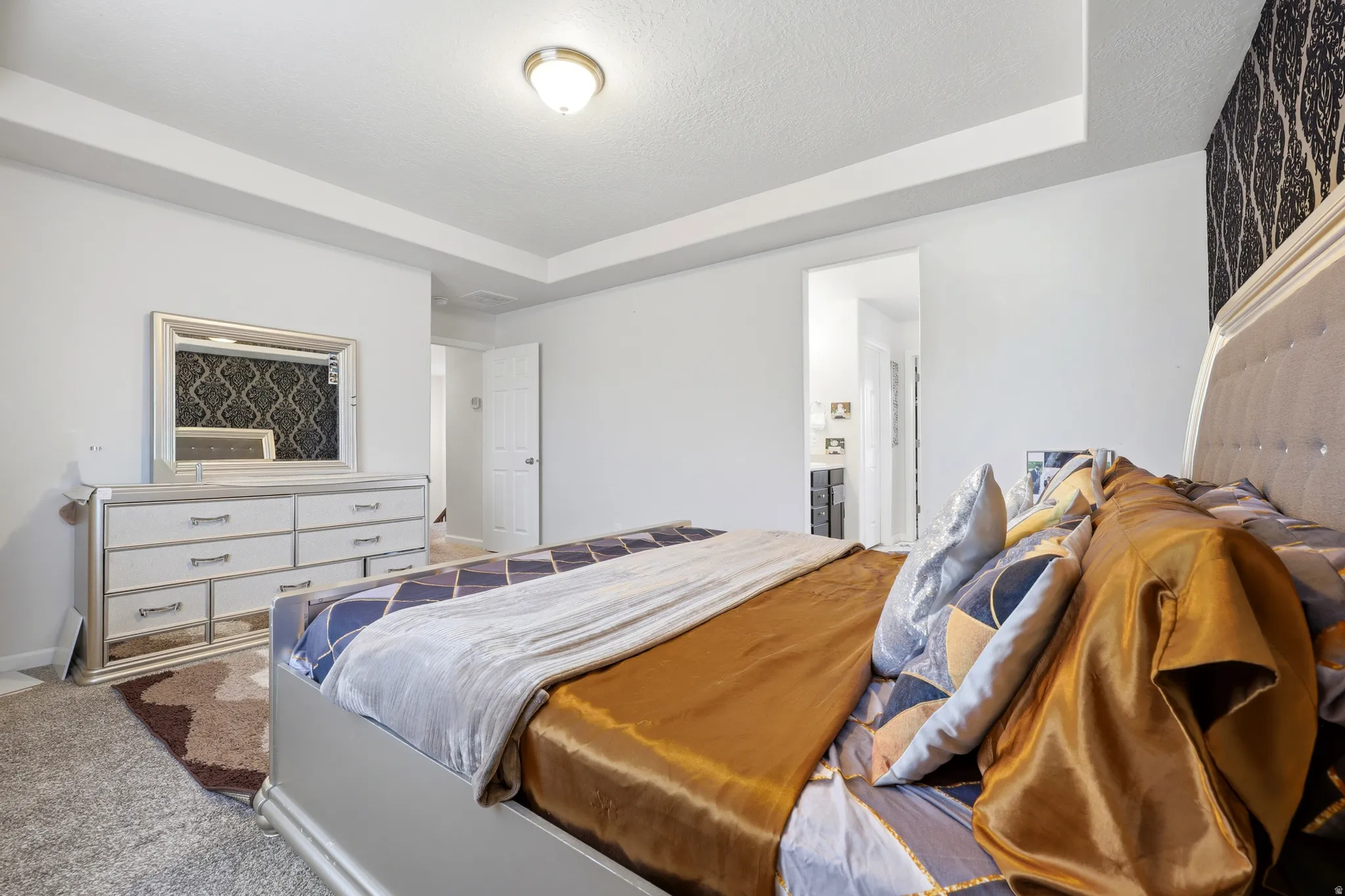Spacious bedroom featuring a tray ceiling, recessed lighting, and wall-to-wall carpeting