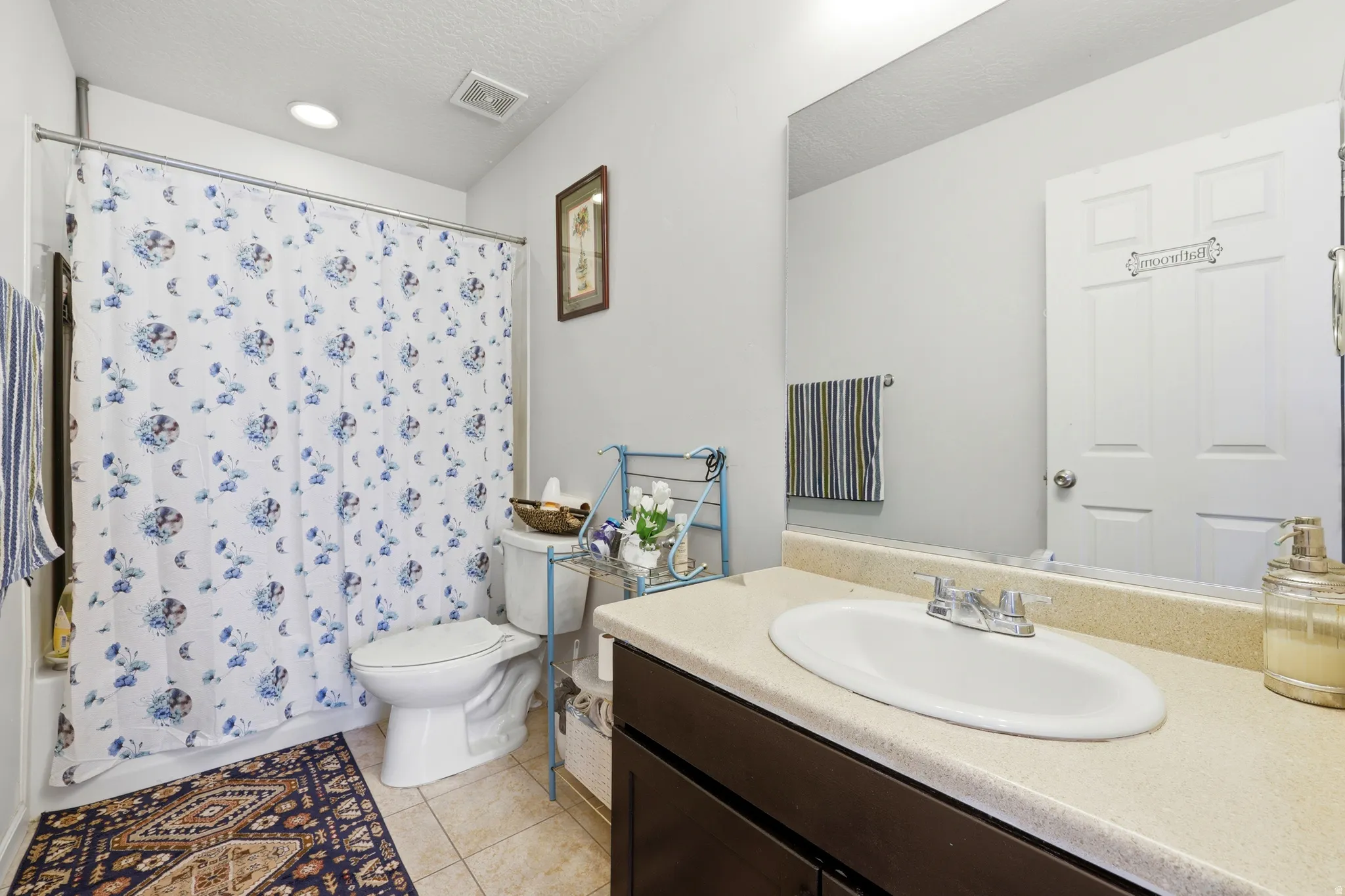 Bathroom featuring a combination shower and tub, tile flooring, and a vanity with an integrated sink and laminate countertop