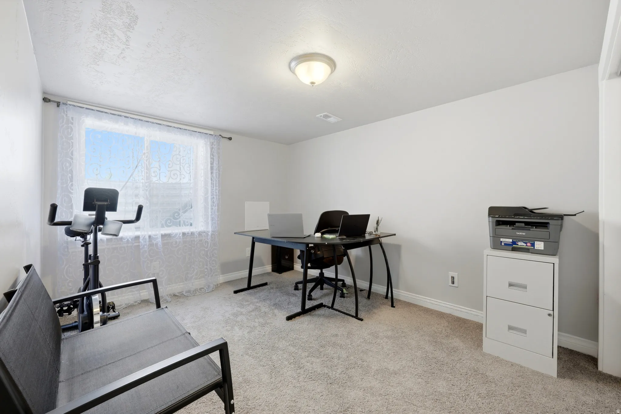 Carpeted room with a large window, light-toned walls, and a ceiling-mounted light fixture