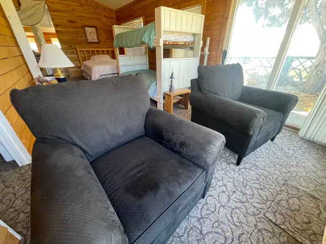 Wood-paneled interior walls define this room featuring large-format windows, a built-in bunk bed structure, and patterned carpeting