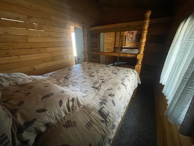 Wood-paneled interior walls characterize this space, featuring a built-in bed frame with turned wood posts
