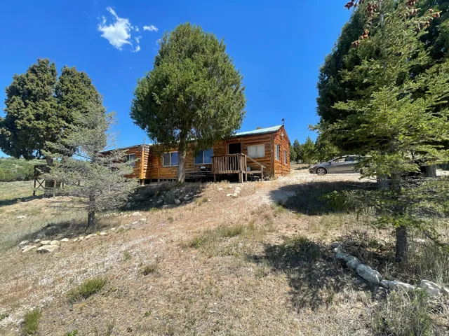 Rustic log cabin exterior with a pitched metal roof, prominent front porch, and natural wood siding