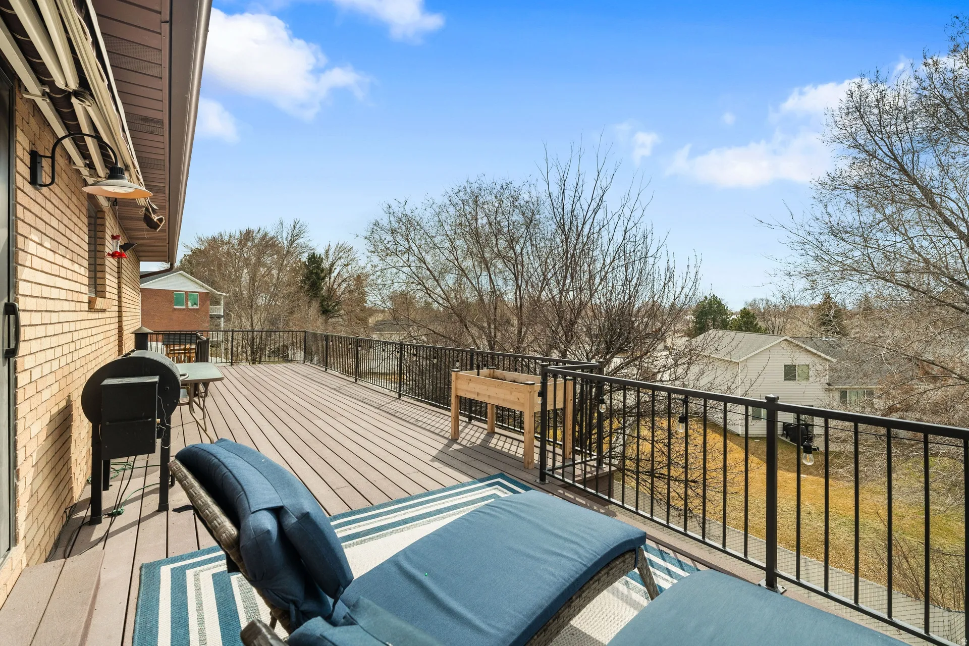 Spacious outdoor deck featuring composite decking, black metal railing, and a brick exterior