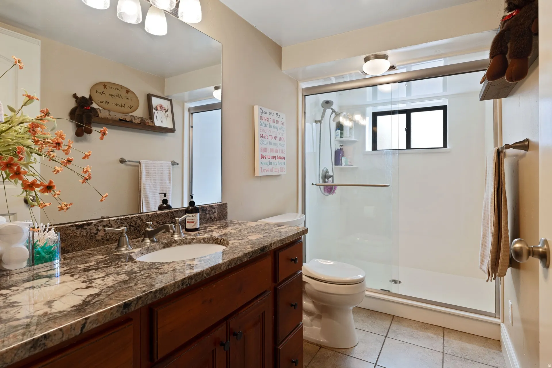 Bathroom featuring a single vanity with stone-finish countertop, undermount sink, and dark wood cabinetry