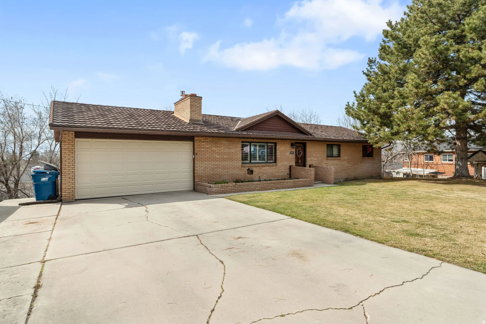 Brick exterior home with an attached two-car garage, featuring a shingled roof and a front lawn