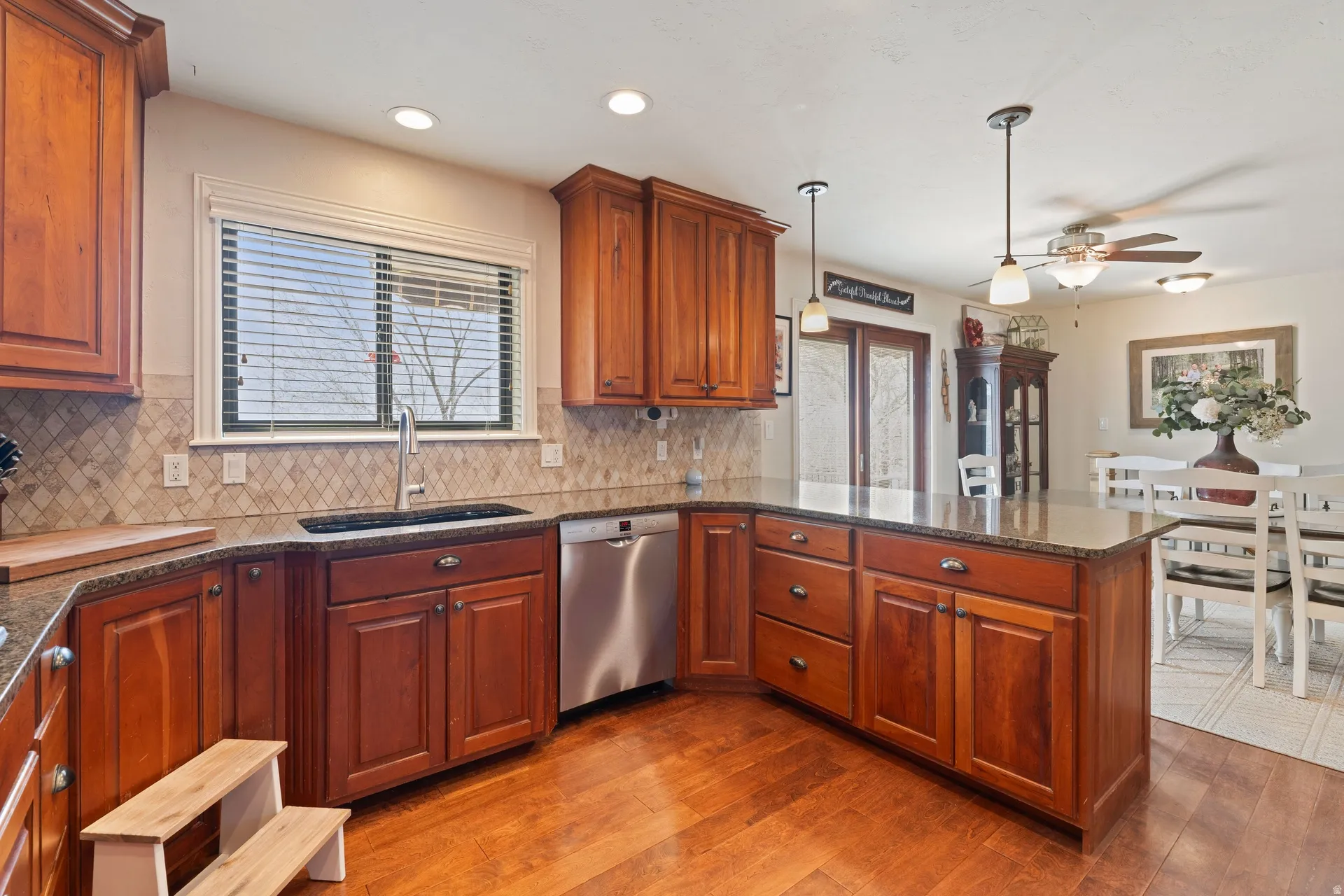 Kitchen featuring wood-finish cabinetry, granite-style countertops, a tiled backsplash, and stainless steel appliances