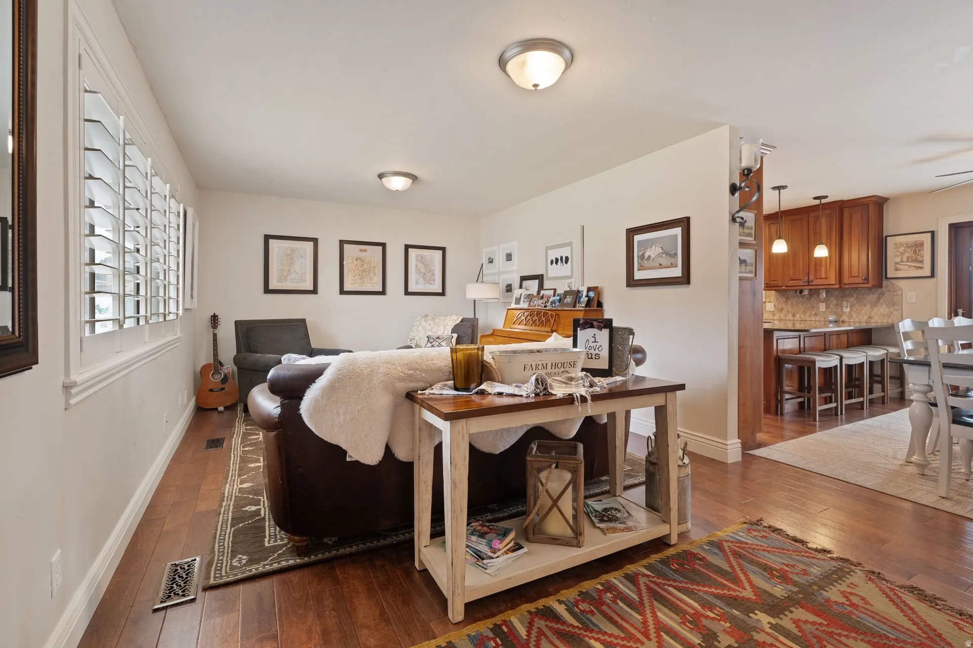 Living area featuring hardwood-finish flooring, white plantation shutters, and recessed lighting