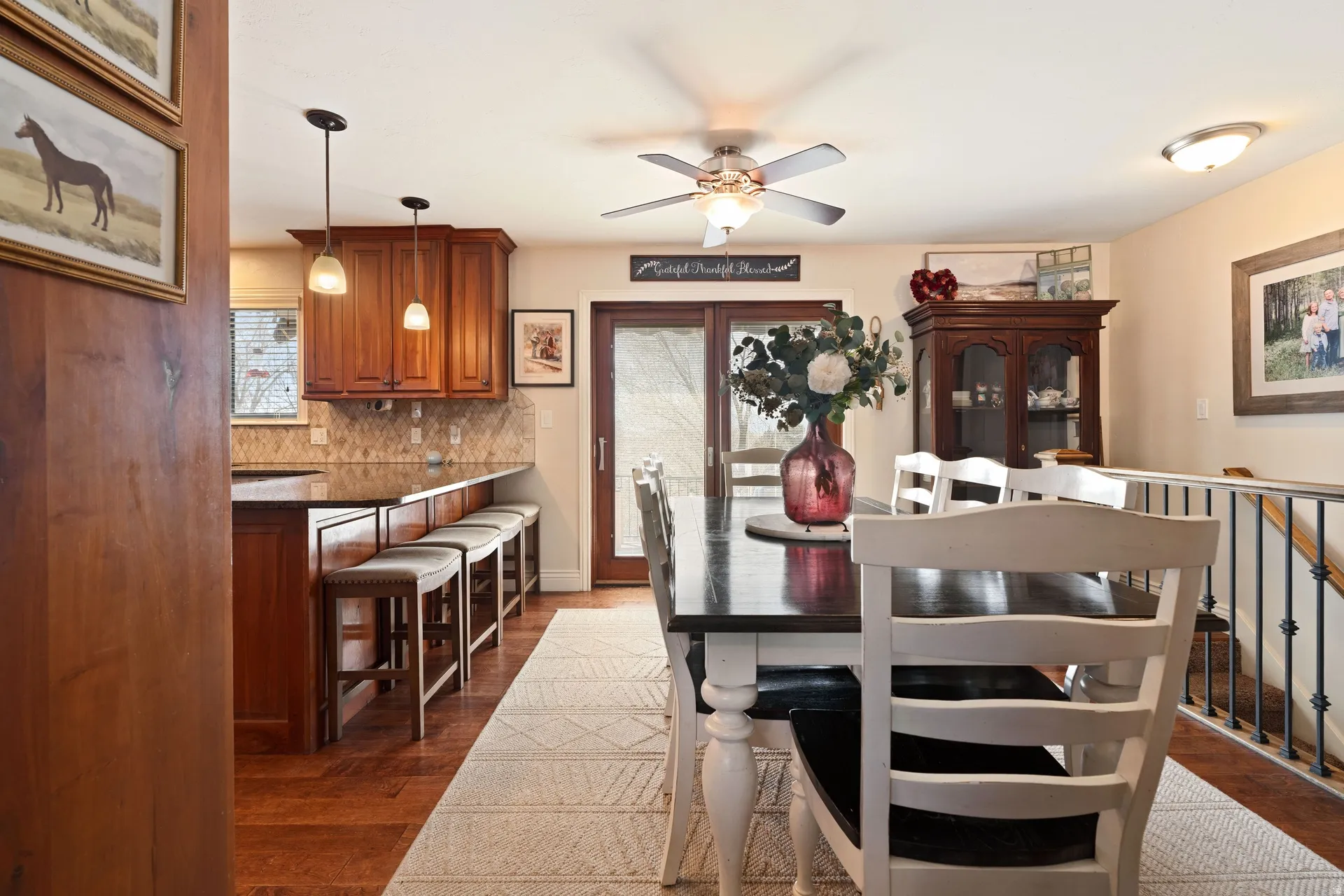 Open-concept dining area featuring wood-finish flooring, a ceiling fan, and access to a glass-paneled exterior door