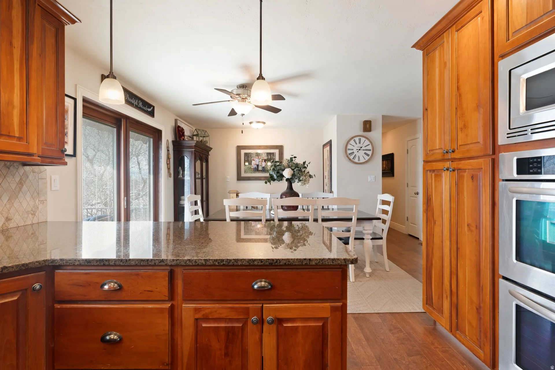 Kitchen island with a polished countertop, wood-finish cabinetry, and stainless steel appliances, including a built-in microwave and oven