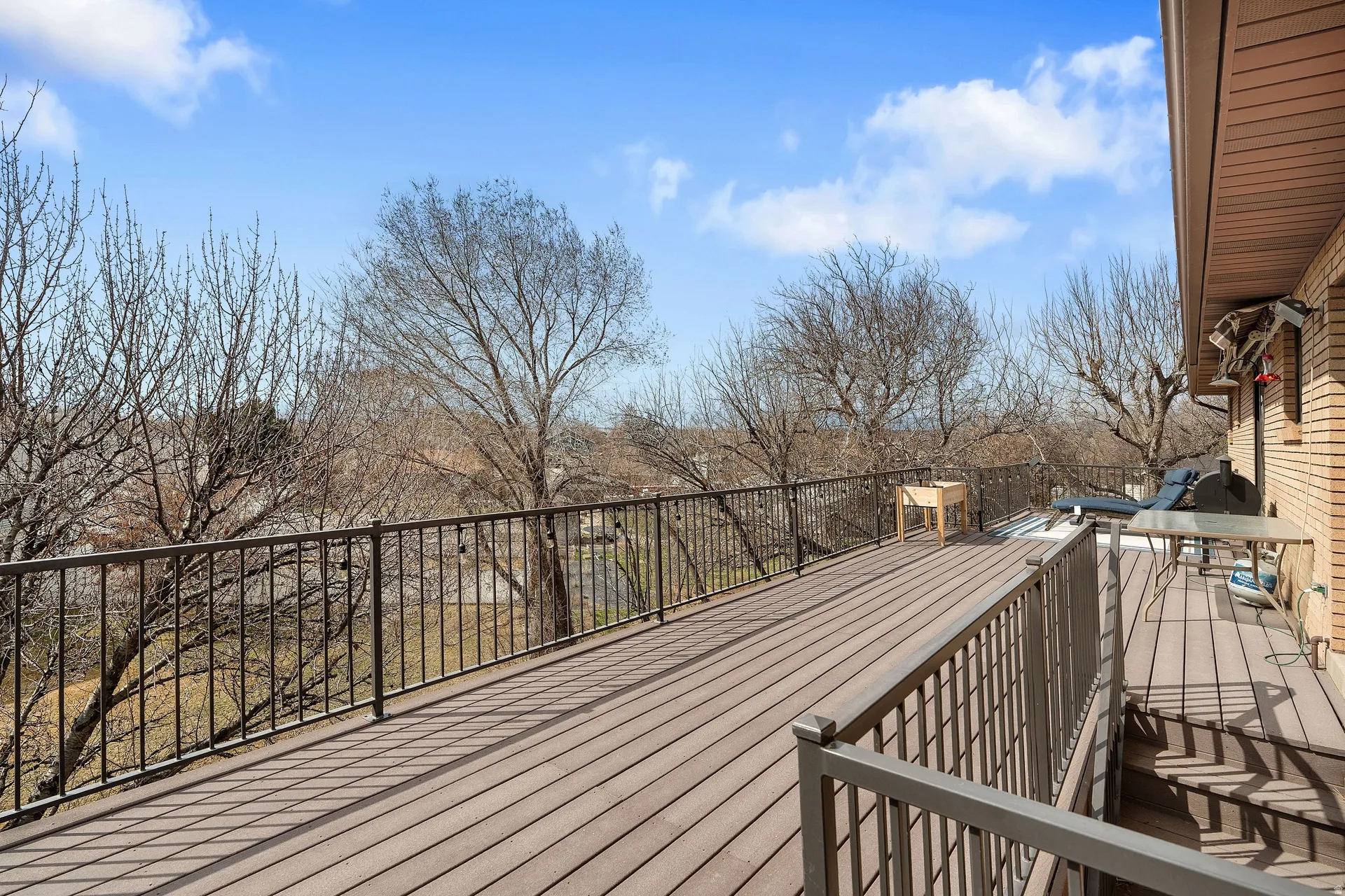 Expansive outdoor deck featuring composite decking, dark metal railings, and a brick exterior wall