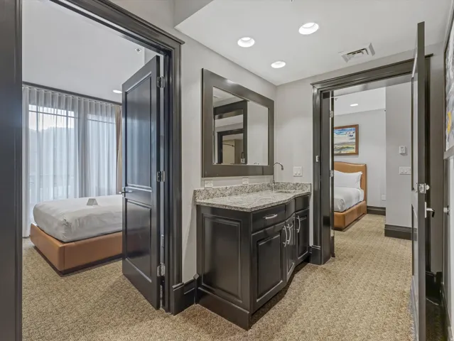 Compact wet bar featuring a speckled countertop, undermount sink, and dark wood cabinetry