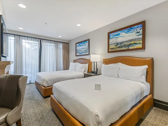Spacious room with dual beds featuring upholstered headboards, recessed lighting, and direct access to an outdoor area through glass panel doors