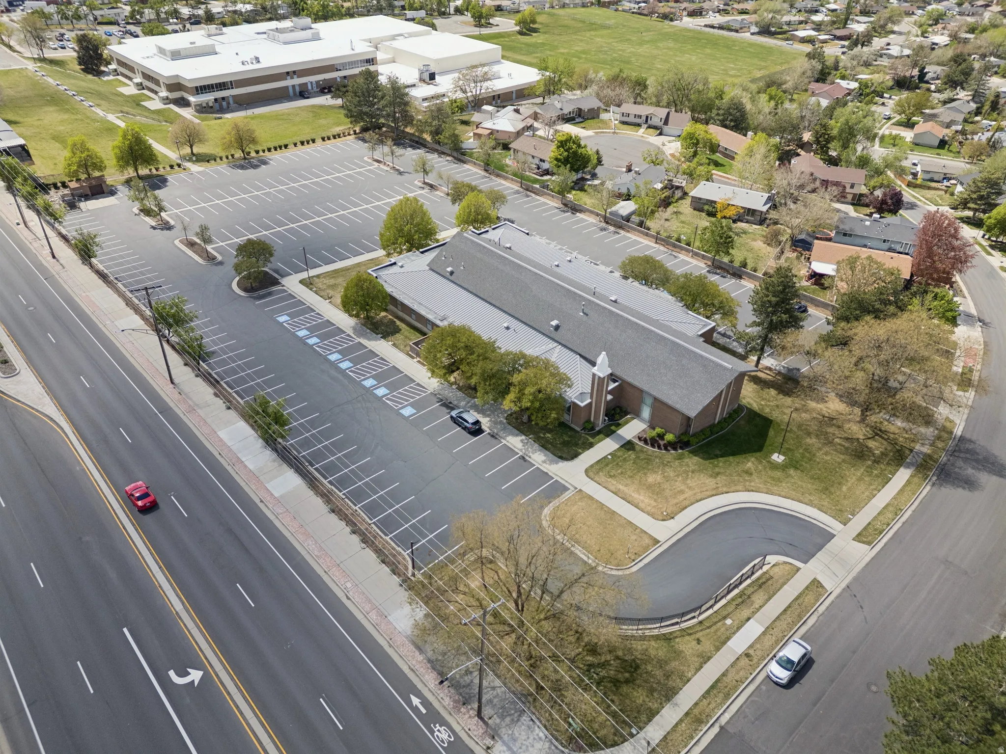 Large parking lot with marked spaces, bordered by a main road and residential streets