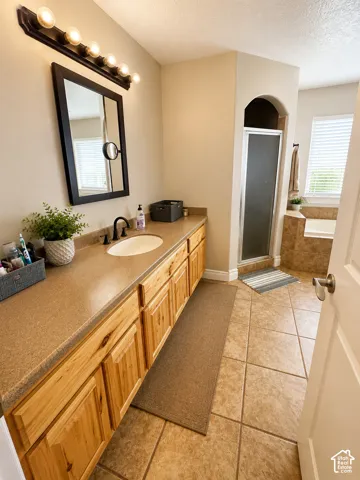 Spacious bathroom featuring a double vanity with light wood cabinetry and a solid surface countertop