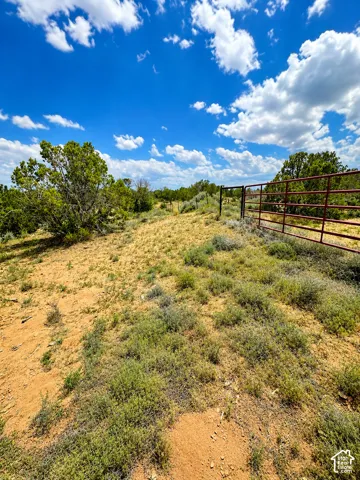 Expansive open land featuring natural vegetation and a metal gate