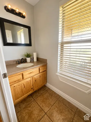 Bathroom featuring a vanity with a light wood-finish cabinet, an integrated sink, and a speckled countertop