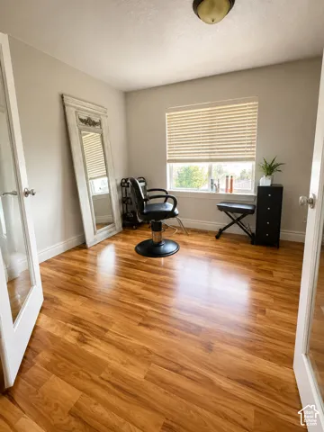 Room featuring warm wood-finish flooring, light neutral wall paint, and white trim