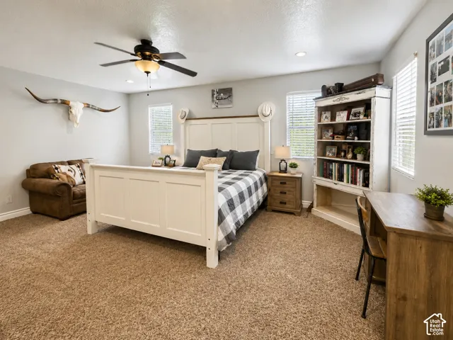 Spacious bedroom featuring light-colored walls, recessed lighting, a ceiling fan with integrated lighting, and multiple windows with blinds