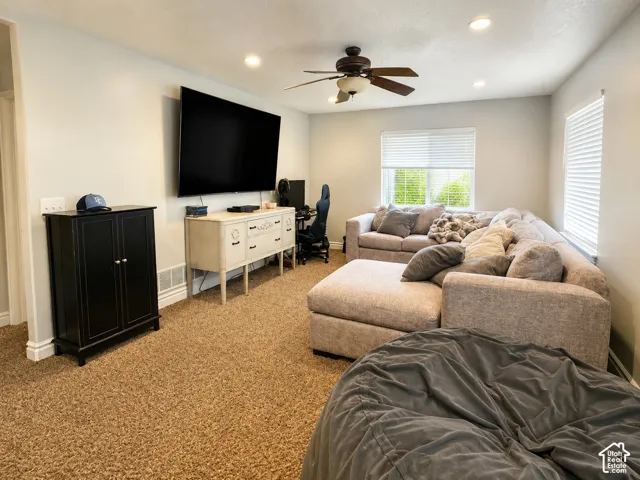 Carpeted living area featuring recessed lighting, a ceiling fan, and multiple windows with blinds
