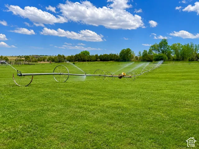 Expansive green field featuring an active irrigation system with multiple sprinklers