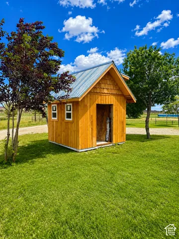 Wood-sided outbuilding with a corrugated metal roof and a gable accent featuring decorative shingles