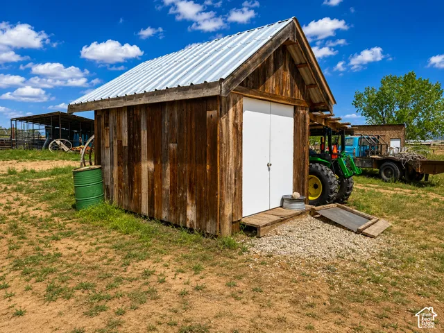 Wood-sided storage shed featuring a corrugated metal roof and white double doors